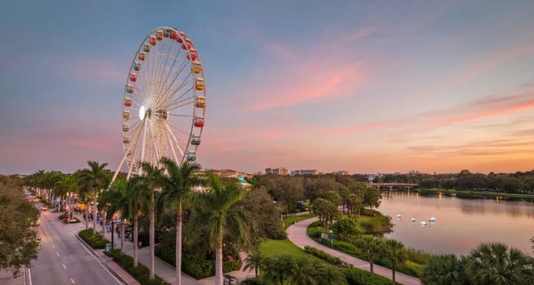 Lugares turisticos en Orlando FL: noria de ICON Park, palmeras y lago urbano al atardecer en una guía de atracciones y parques 2026