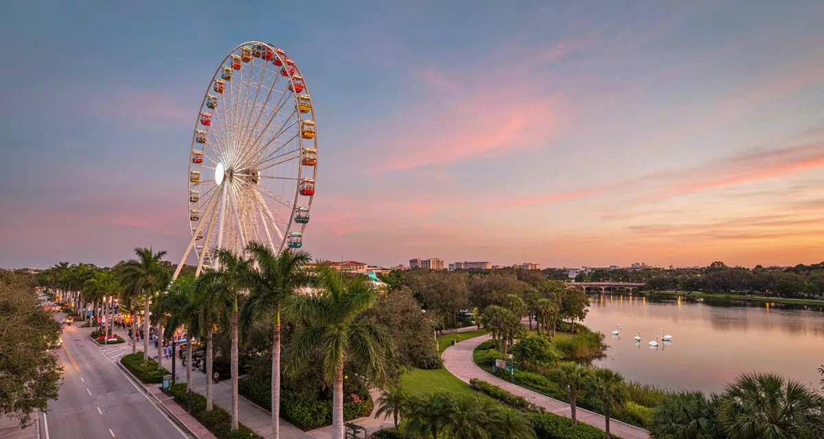 Lugares turisticos en Orlando FL: noria de ICON Park, palmeras y lago urbano al atardecer en una guía de atracciones y parques 2026